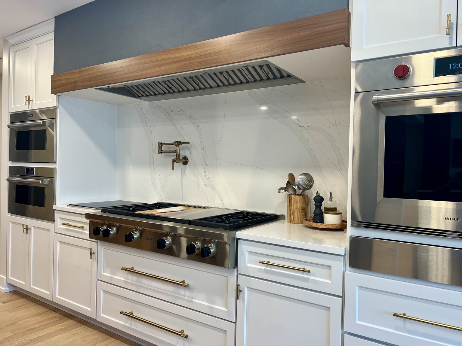 Custom white kitchen with walnut range hood detail and professional appliances