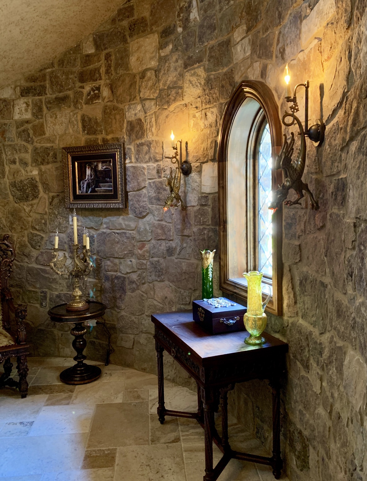 Curved custom staircase with ornamental ironwork, natural stone walls and arched wood entry door.