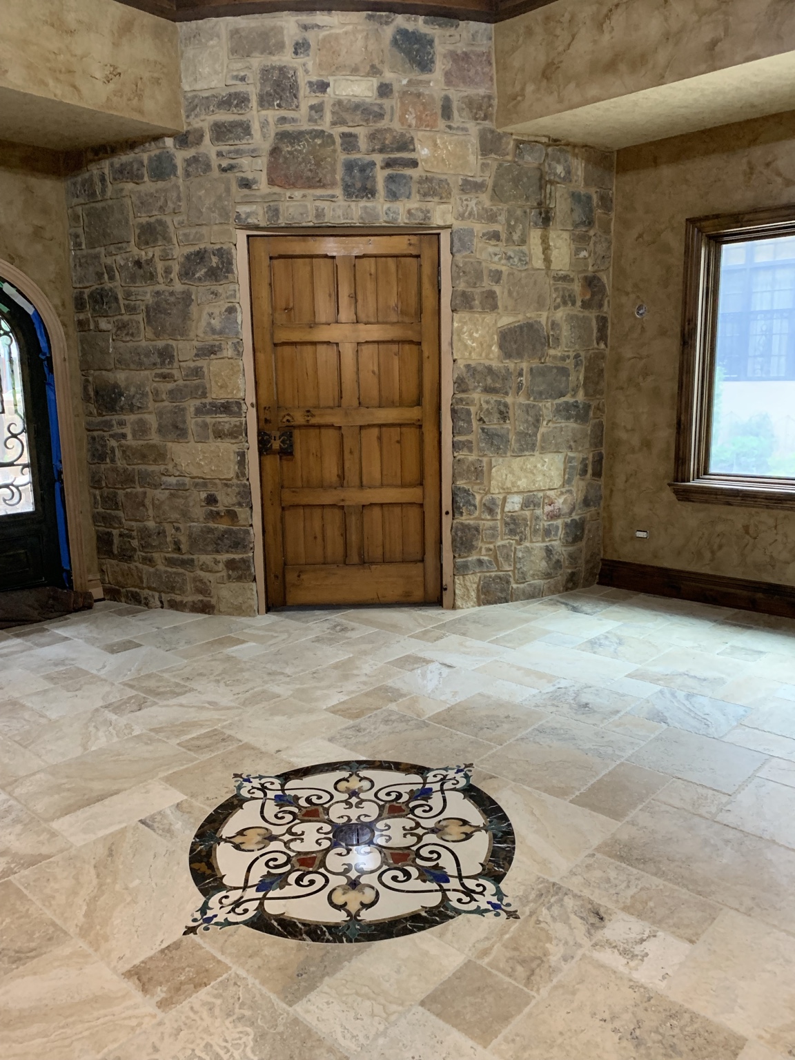 Custom stone floor medallion, natural stone walls and handcrafted wood door.