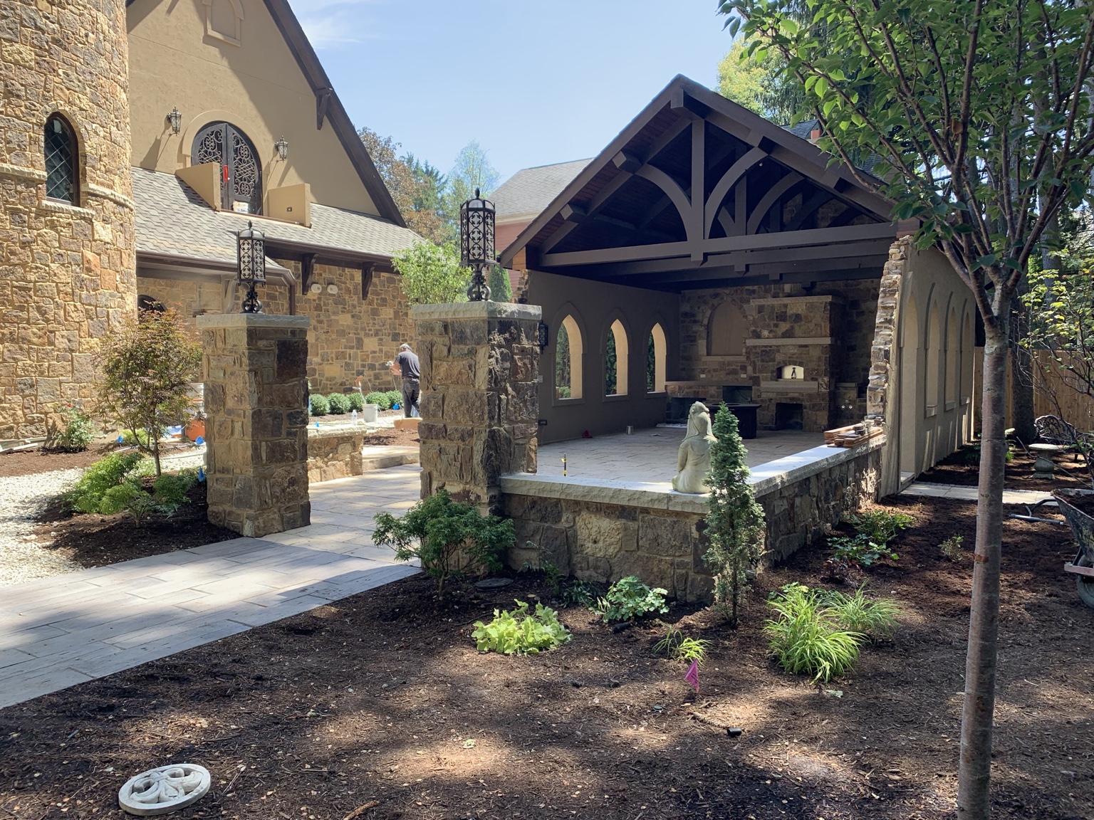 Completed stone and timber outdoor pavilion with fireplace and landscaped courtyard.